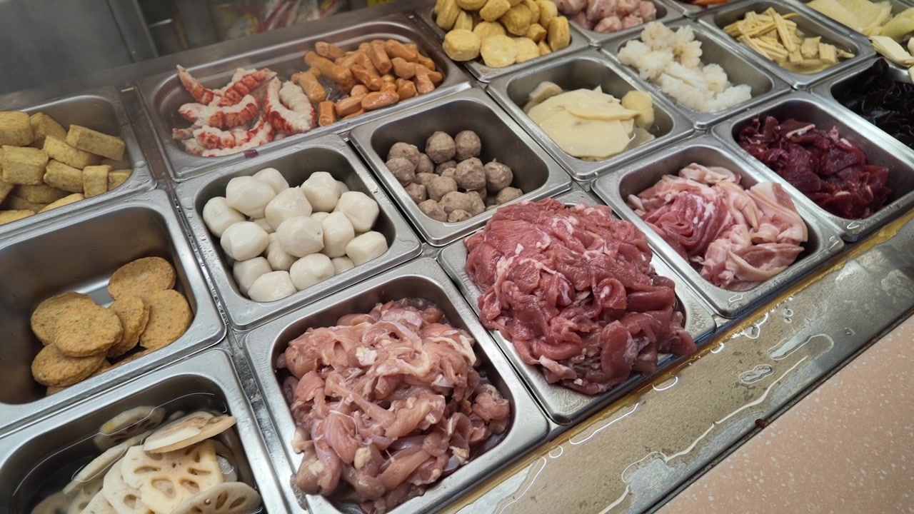 Ingredientes crudos variados en bandejas de metal para olla caliente