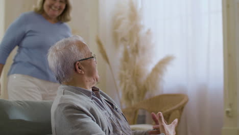 happy senior wife putting face mask on husband at home