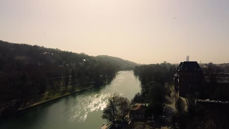 Dramatic-drone-shot-during-golden-hour-showing-river,-bridge,-trees,-castle-and-city