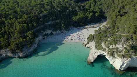 Luftaufnahme-Des-Berühmten-Strandes-Von-Menorca-In-Spanien,-Cala-Mitjana,-Mit-Booten,-Die-In-Küstennähe-Vor-Anker-Liegen