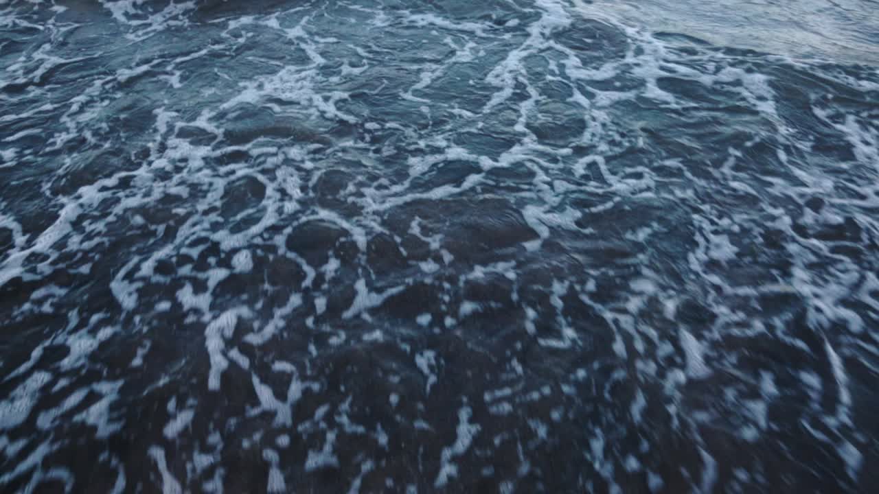 Vidvinkelbilde av havbølger som slår inn mot stranden.