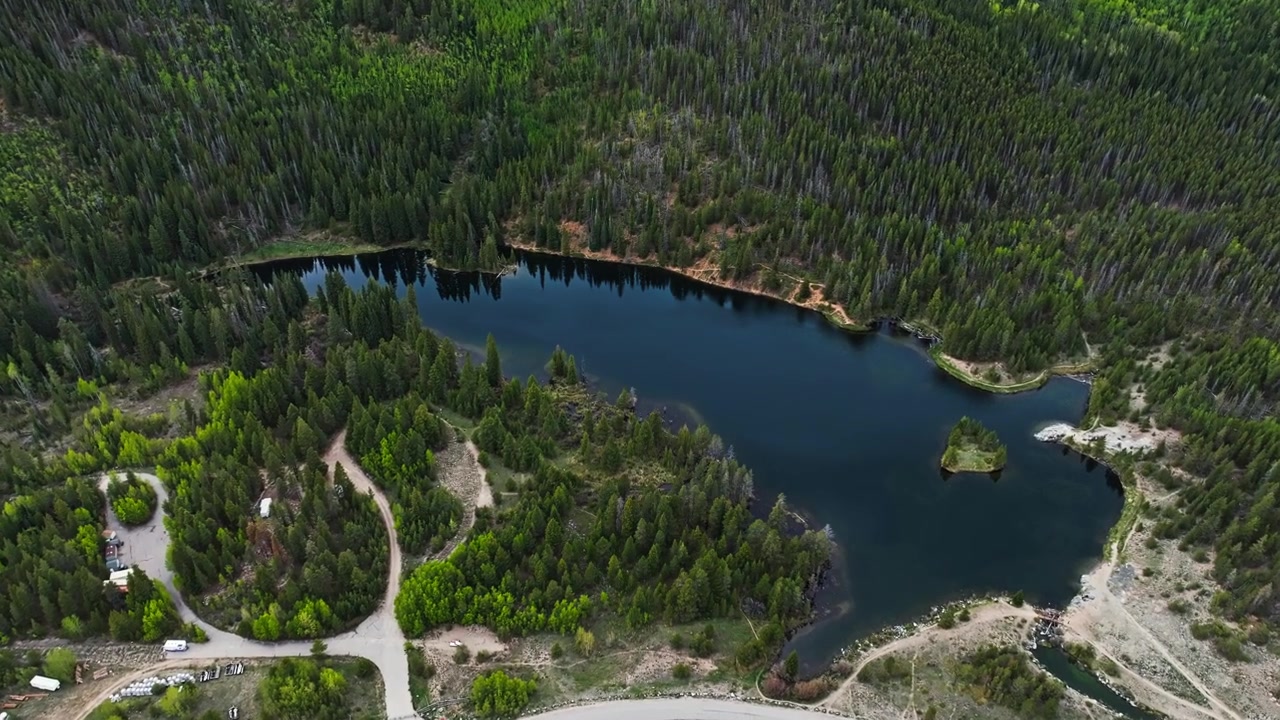 Lago Officer's Gulch circondato da una foresta di conifere in un paesaggio alpino, ripresa aerea con drone in dolly che si inclina verso il basso