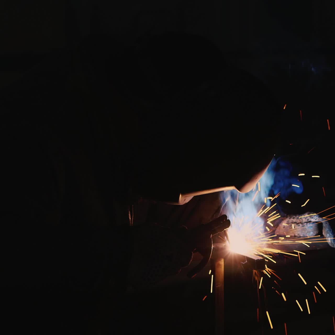 A welder in a protective helmet and clothes welds as sparks fly 5