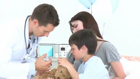 doctor jugando con un niño pequeño recuperándose en el hospital y su oso de peluche