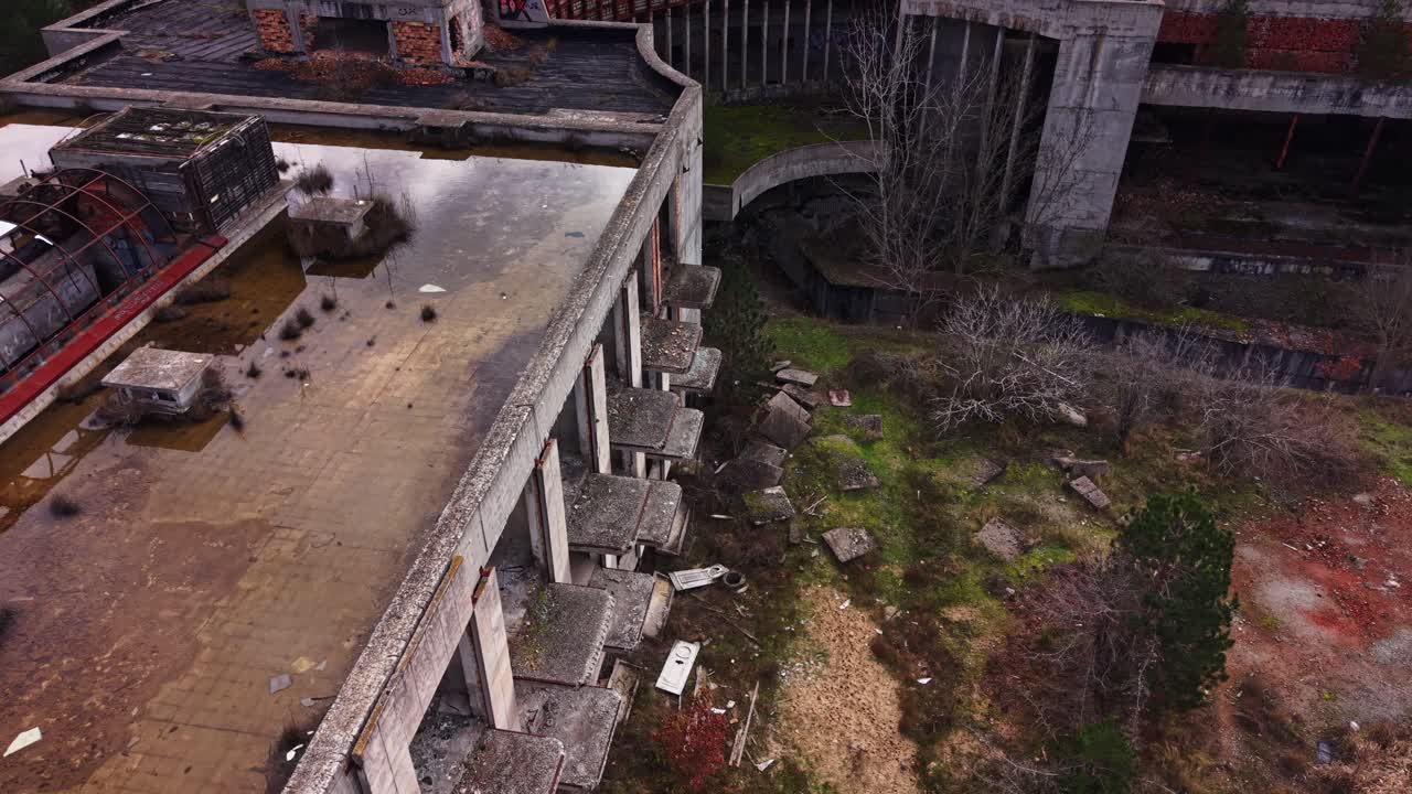 Abandoned industrial site with overgrown vegetation and water pooling