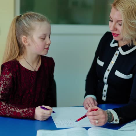 tutor with a primary student. female teacher explains the rule to the schoolgirl individually. creative pedagogue teaching little girl.
