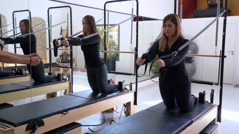 Mujeres-Haciendo-Ejercicio-En-Reformer-Durante-El-Entrenamiento-De-Pilates