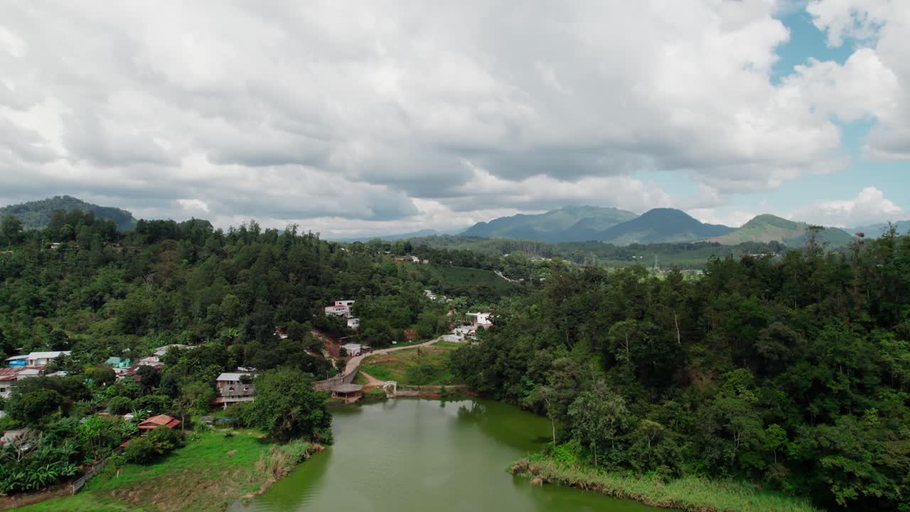 Aerial zoom in shot over Cobán Guatemala, showing a small lake surrounded by forested hills and scattered houses