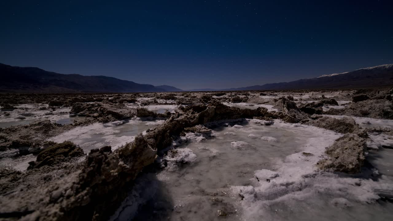 lapso de tiempo de movimiento deslizante de formaciones de cristal de sal y piscinas de agua salada a la luz de la luna