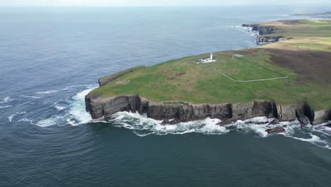 aerial view of a lighthouse on coastal cliffs with crashing waves