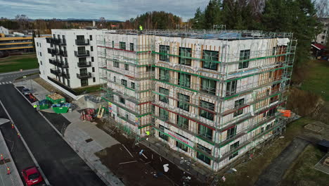 Building-under-construction-wrapped-in-scaffolding-to-support-workers,aerial