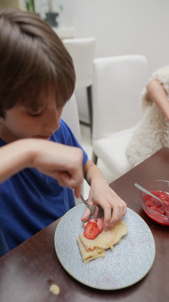 Child eating pancakes with strawberries