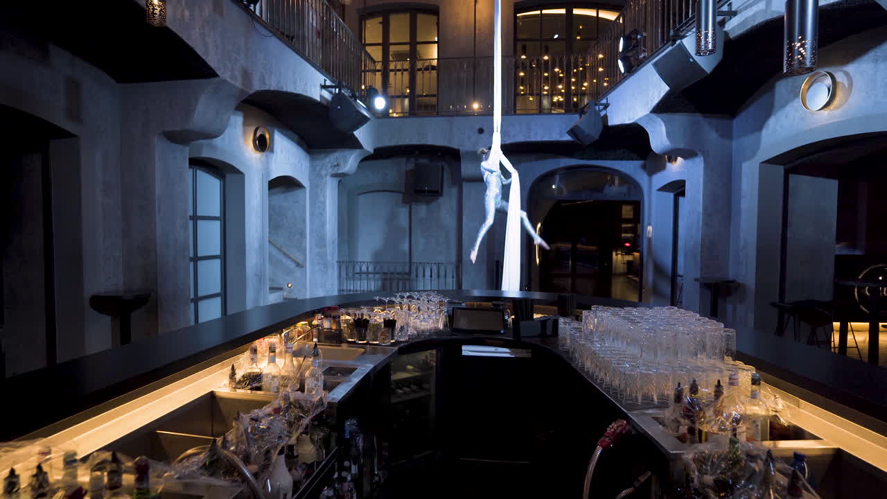 바 위의 실크에 십자가와 댄스 포즈를 취하는 여성 곡예사