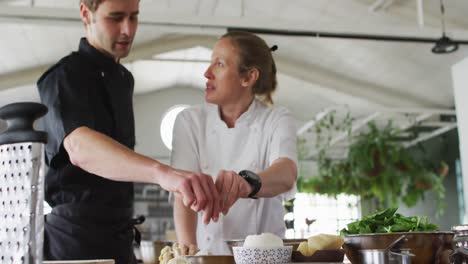 caucasian female and male chefs making dough in a bowl