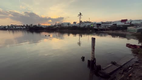puesta de sol sobre un tranquilo canal con muelle de madera y edificios