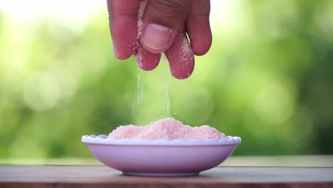 Hand-of-people-grab-himalayan-salt-on-the-bowl-and-pouring-it