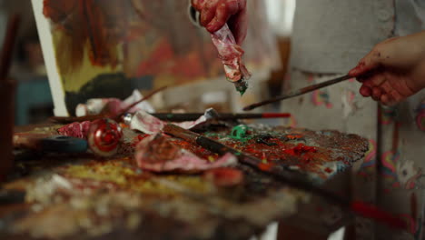 children hand mixing paint on palette