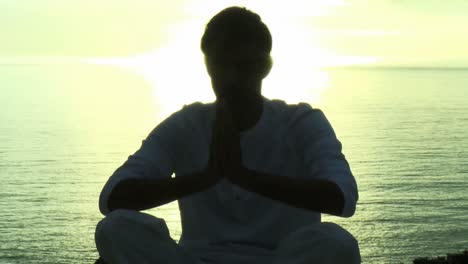 man doing yoga by the sea