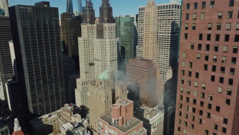 Smoking-historic-multistorey-building-chimney.-Old-hotel-between-modern-skyscrapers-in-midtown.-Tilt-down-on-rooftop.-Manhattan,-New-York-City,-USA