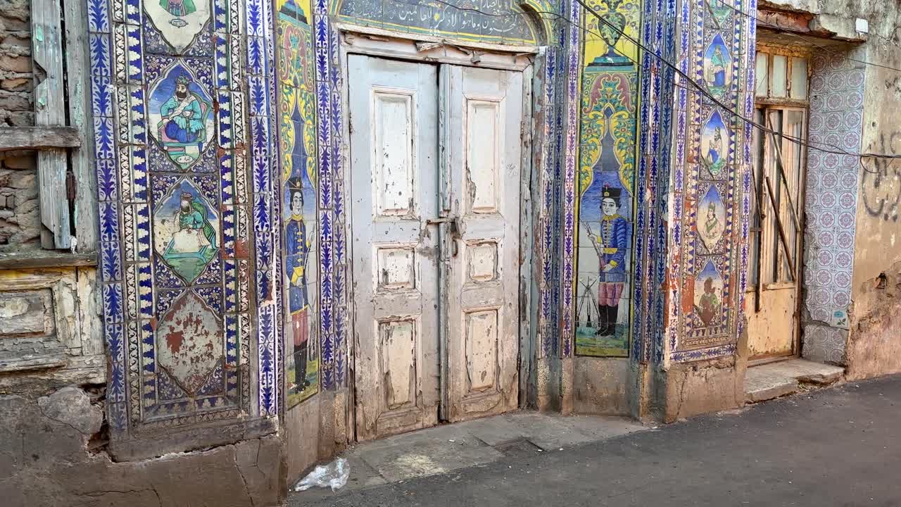 Walking tour in walkway in Rasht old city town in front of an Persian ancient colorful historical workshop landmark gate with blue tiles wall of love fame in down town in a farmer local people market