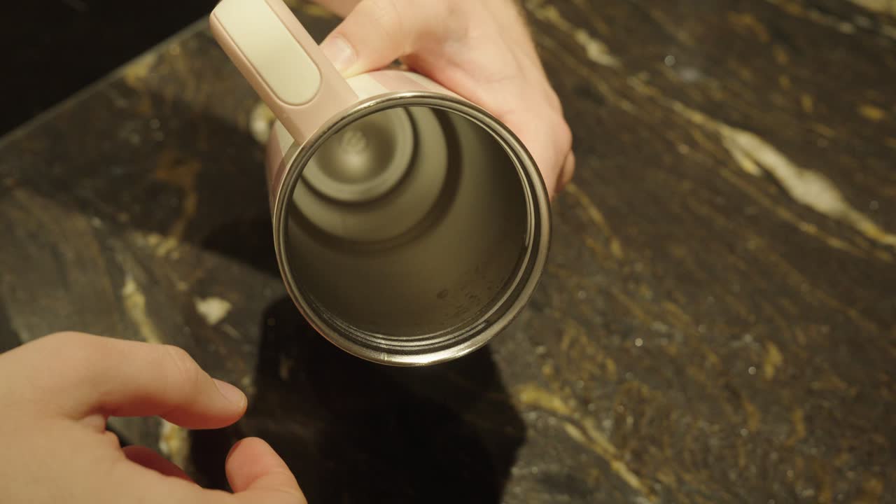 A person cleans a thermos bottle, highlighting hygiene, bacteria prevention, and the importance of regular cleaning for health and safety