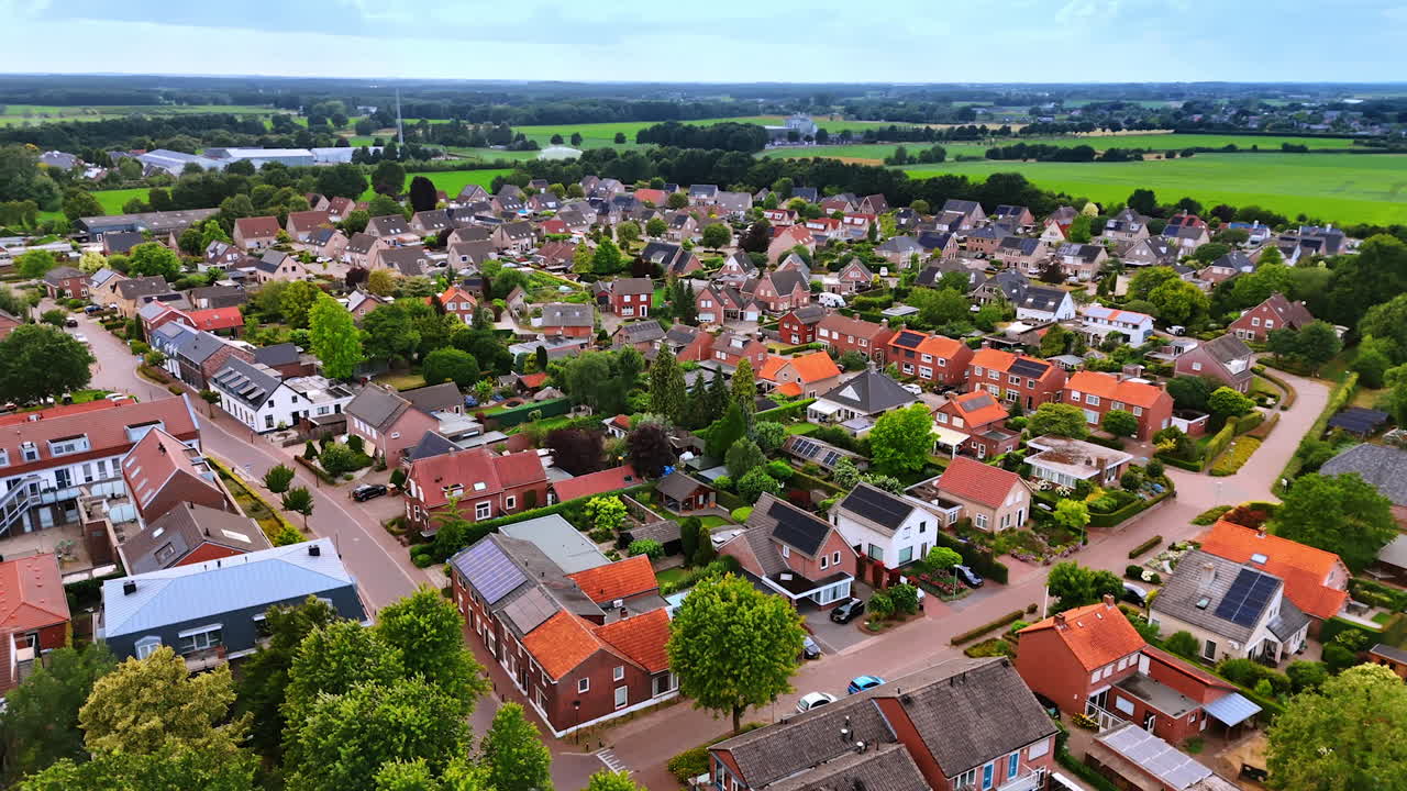 Overview of a quaint rural neighborhood. Aerial view of a tranquil village with green fields, tidy homes, winding roads, and blooming gardens