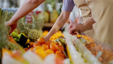 Nahaufnahme-Von-Ein-Paar-Supermarktmitarbeitern,-Einem-Mann-Und-Einem-Mädchen,-Die-Waren-Auf-Der-Zitrusfruchttheke-In-Einem-Supermarkt-Auslegen