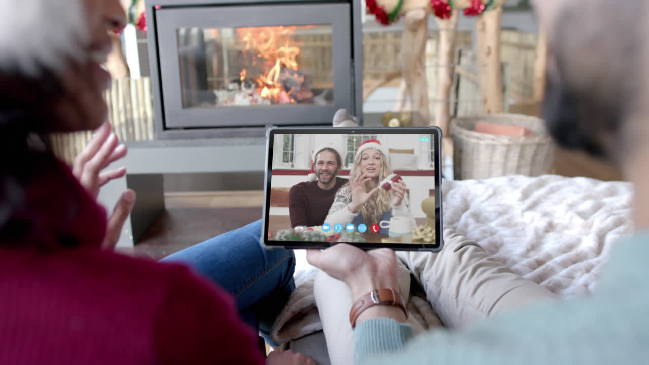 Due coppie felici e diverse in videochiamata di Natale su tablet, al rallentatore