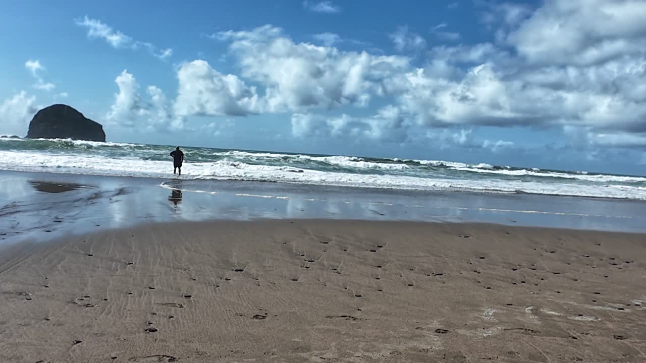 Sweeping view of Trebarwith Strand beach with gentle waves and rocky cliffs. Sunlight illuminates the sand creating a tranquil, untouched atmosphere. Captivating coastal scenery