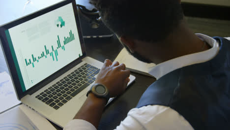 Side-view-of-young-black-businessman-writing-on-diary-while-using-smartwatch-in-a-modern-office-4k