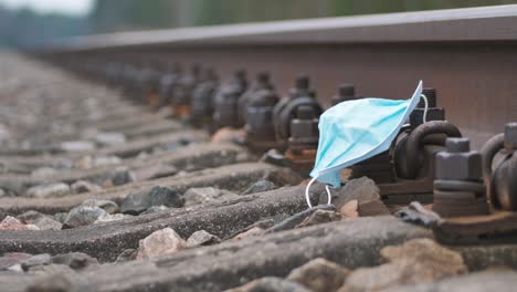 the medical disposable blue protective mask lies on the rail, the coronavirus covid-19 virus waste