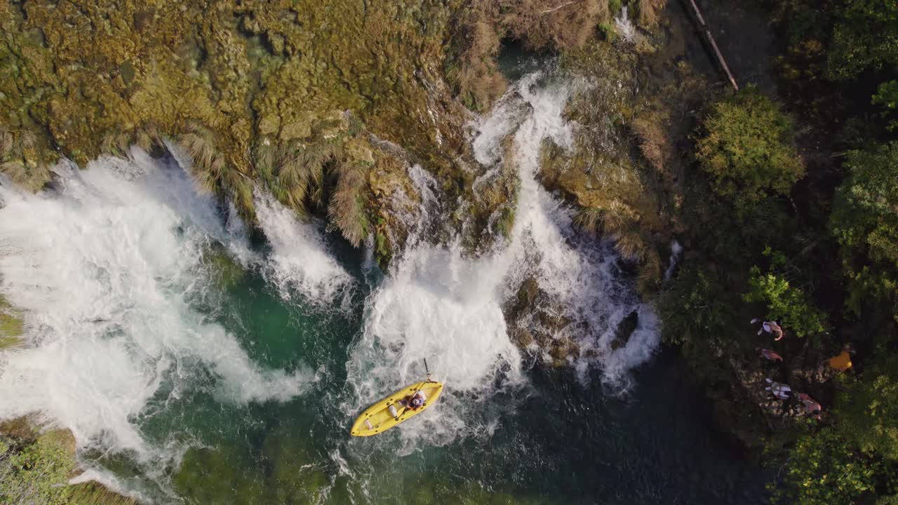 Vista dall'alto di un kayak giallo che scende una piccola cascata sul fiume Zrmanja in Croazia, aerea.