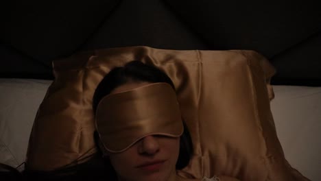 Young-Caucasian-model-resting-sleeping-at-night-alone-in-bed-with-sleeping-mask