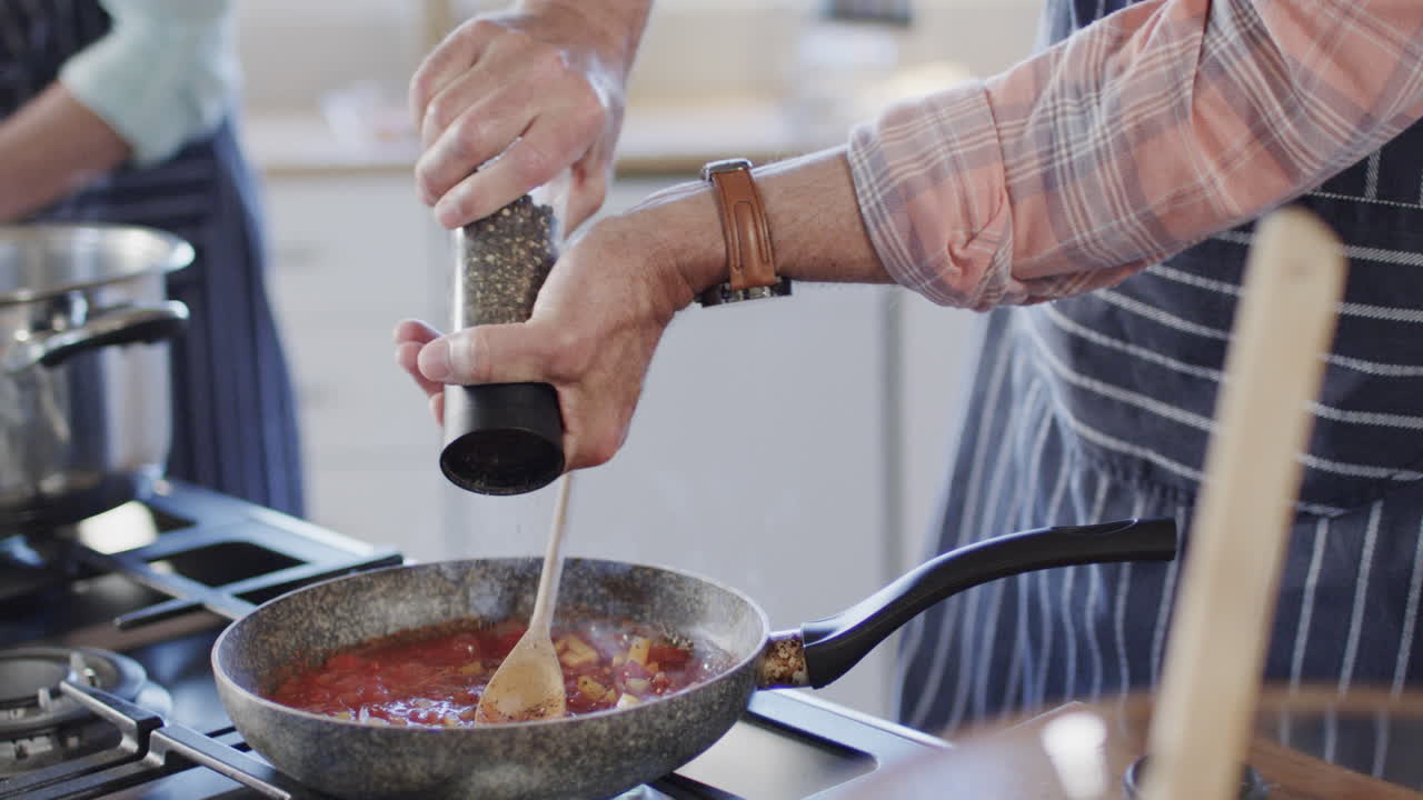 pareja caucásica de mediana edad preparando comida, cocinando en la cocina en casa, cámara lenta