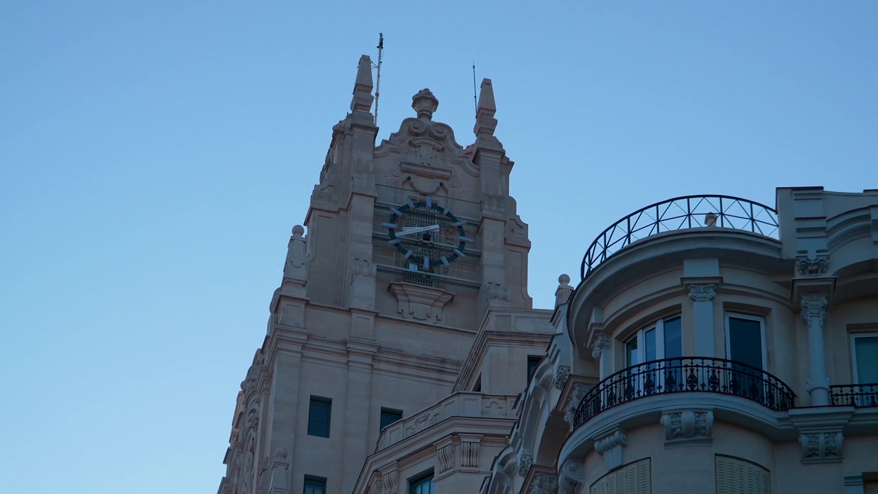 Un'inquadratura dettagliata dal basso della sontuosa torre dell'orologio del Palacio de Cibeles a Madrid durante l'ora blu. Cattura la storica architettura spagnola e il patrimonio urbano.