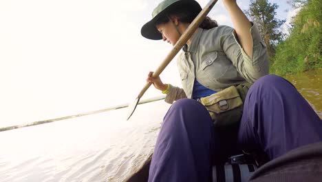 Una-Hermosa-Chica-Aventurera-Con-Un-Sombrero-De-Viaje-Está-Remando-En-Un-Bote-Tradicional-En-El-Río-En-La-Selva-Amazónica-Madagascar-Brasil-áfrica-América