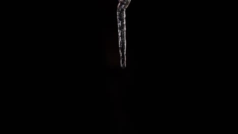 Time-lapse-sequence-of-a-growing-icicle-in-front-of-a-black-background