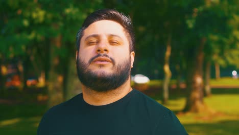 handsome beard man slowly breathing with eyes closed at the park in slow motion