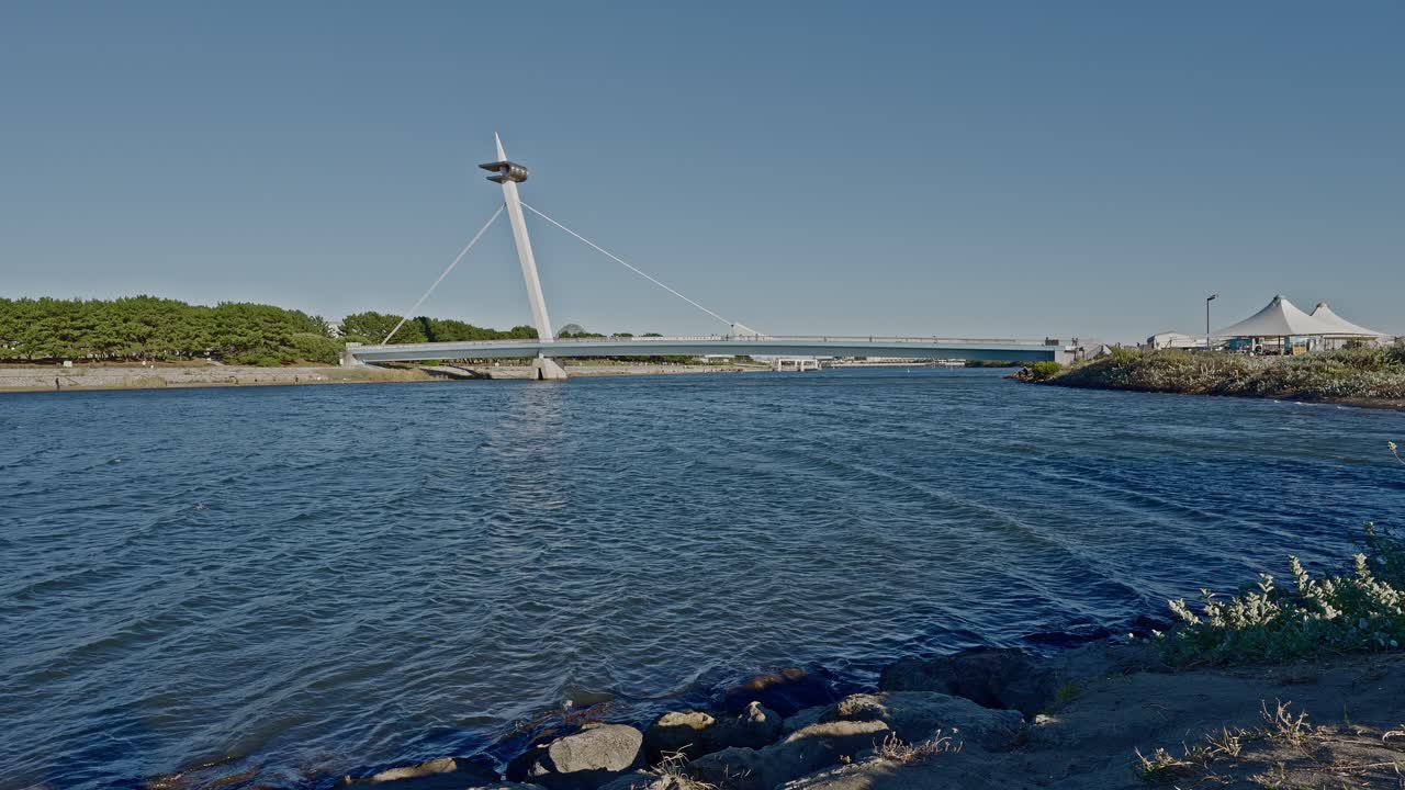 The iconic Kasai Nagisa Bridge, designed like a sailboat mast, connecting the West Beach to the city under a vast Tokyo sky
