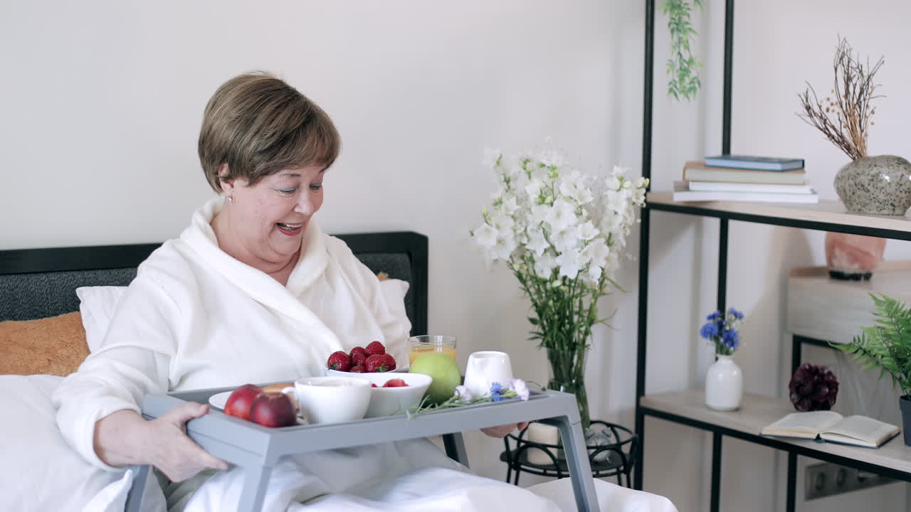 Felice signora anziana che si sveglia e si gusta la colazione a letto