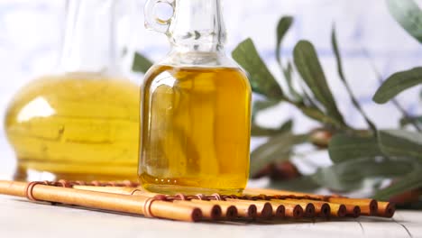 Bottle-of-olive-oil-and-olive-leaves-on-yellow-,