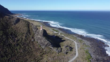 flying towards a lighthouse, high on a cliff in cape palliser, new zealand