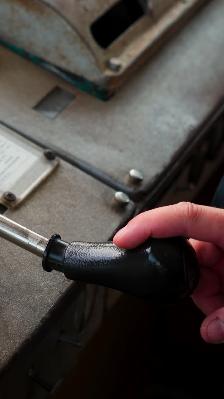 Close-up of a hand operating a lever on a metal control panel