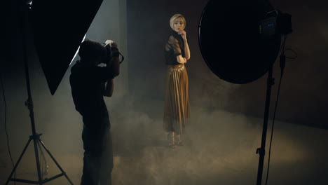 high angle view of caucasian young female model posing in the dark studio while the photographer taking shots of her