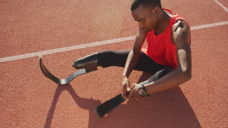 disabled mixed race man with prosthetic legs sitting on racing track