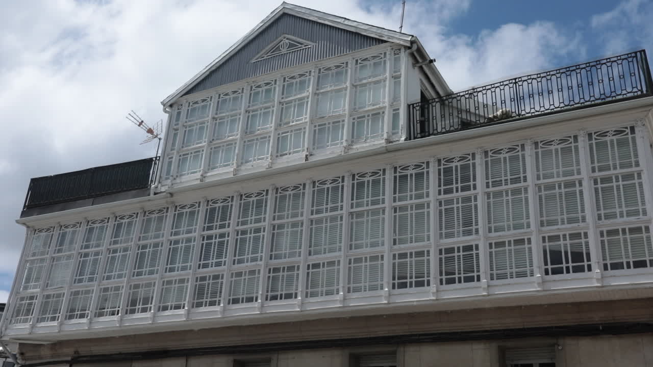 White glass-paneled building against a cloudy sky in a coastal town