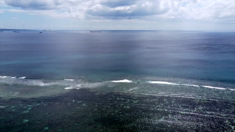 aerial : flight over the ocean and giant container ship in background