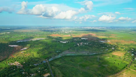 lush green landscape with scattered buildings and a cloudy sky, daytime, aerial view