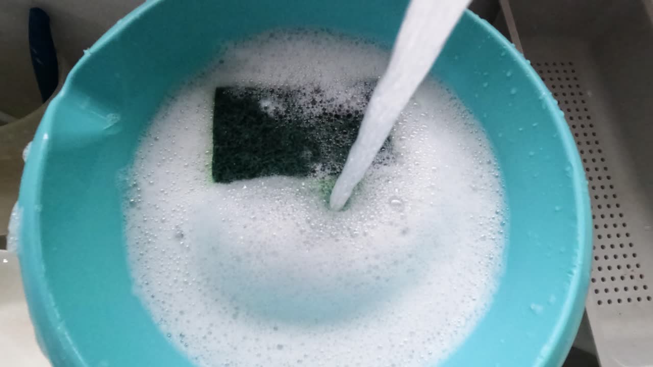 蛇口から水が流れ、石鹸と泡で満たされた青いボウルに注がれる。中には緑のスポンジがあり、スポンジが洗われると泡が立つ。