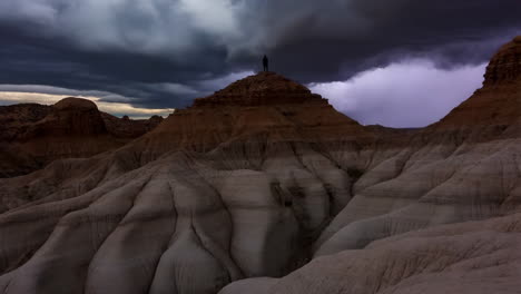 man silhouetted on desert hills beneath a stormy sky